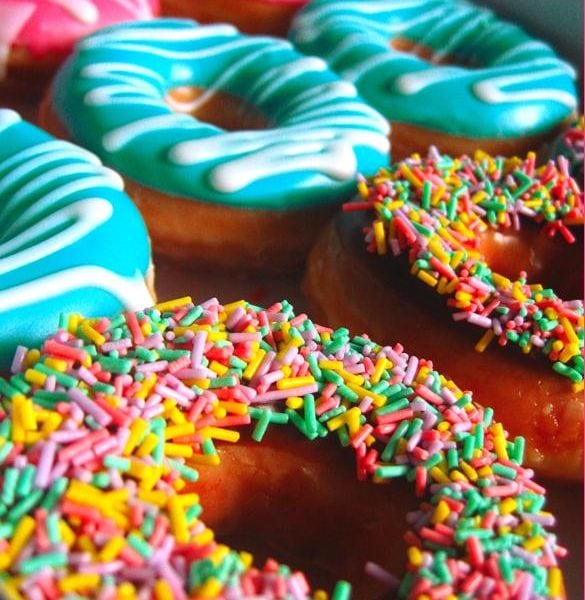 An assortment of donuts. Pink, blue, and rainbow donuts.
