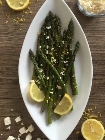 Grilled Lemon Asparagus and Feta Salad placed on a white serving dish. Ingredients include asparagus, lemon, feta.