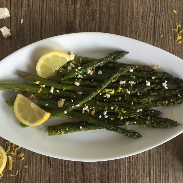 Grilled Lemon Asparagus and Feta Salad placed on a white serving dish. Ingredients include asparagus, lemon, feta.
