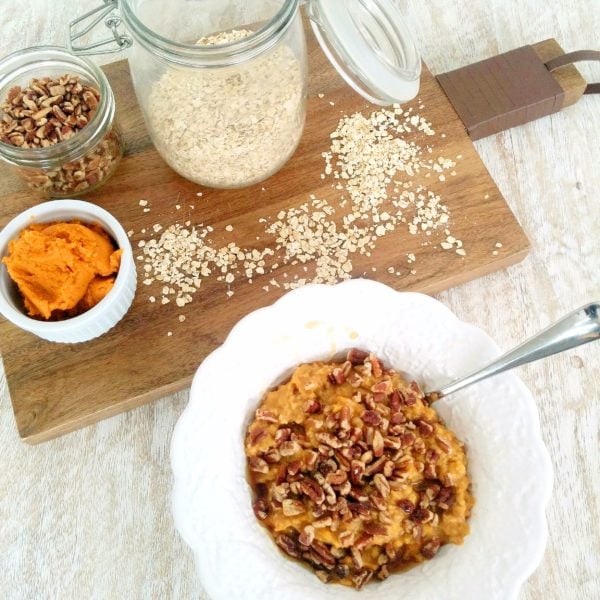 Pumpkin Pecan Oatmeal placed in a white round bowl. Ingredients include quick oats, water, pumpkin pie spice, pumpkin puree, walnuts, maple syrup, nut butter.