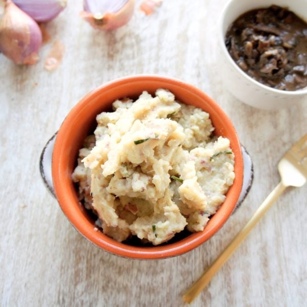 Creamy Red Potato and Cauliflower Mash placed in a round cocotte. Ingredients include red potatoes, cauliflower, garlic, grass fed butter, chives.