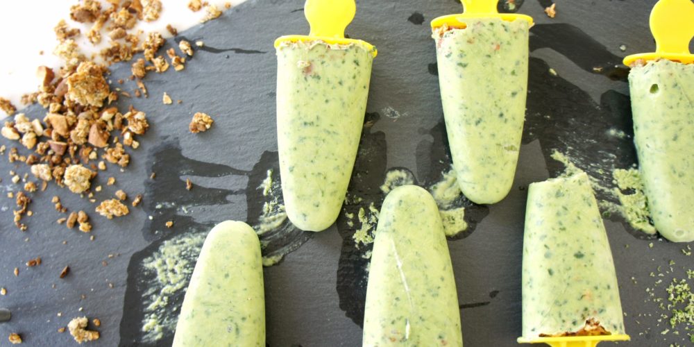 Lime Smoothie Pops placed on a black food photography board. Ingredients include Greek yogurt, kefir, limes, avocado, banana, spinach, granola.