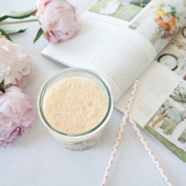 Bridal Smoothie in a glass jar placed beside two straws, a book, and purple peonies.