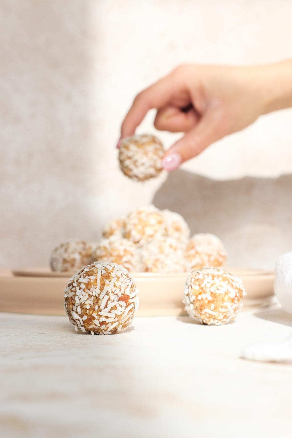Two energy balls are in the forefront with a hand in the background picking up an energy ball from a plate.