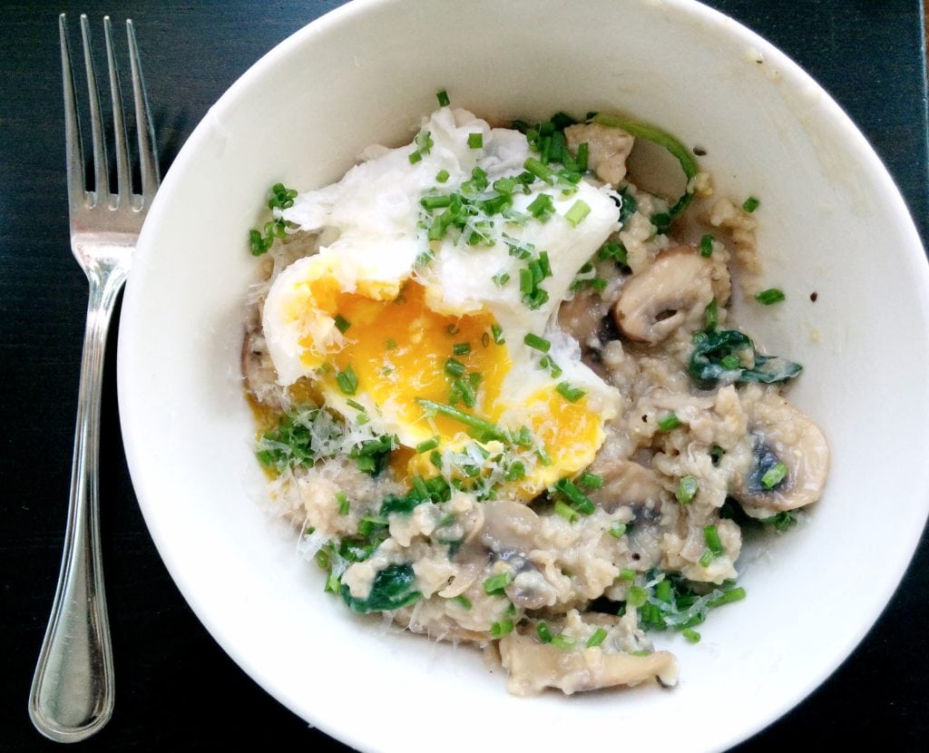 10 minute savory oats with poached egg are in a white bowl. The yolk is cracked and topped with green onion.