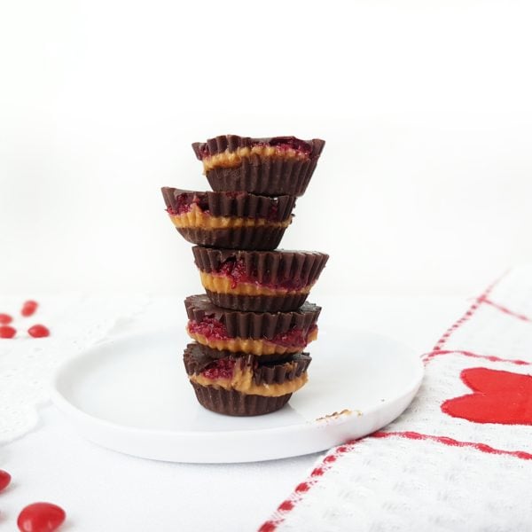 Chocolate PB & J Cups piled on a round white plate. Ingredients include chocolate, chia jam, peanut butter.