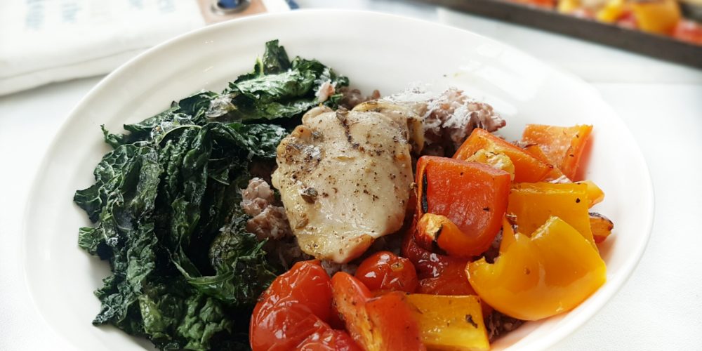 One Pan Greek Chicken with Blistered Tomatoes and Peppers in a white round bowl. Ingredients include bell pepper, cherry tomatoes, chicken thighs, Greek spice mix, lemon.