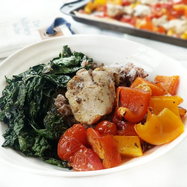 One Pan Greek Chicken with Blistered Tomatoes and Peppers in a white round bowl. Ingredients include bell pepper, cherry tomatoes, chicken thighs, Greek spice mix, lemon.