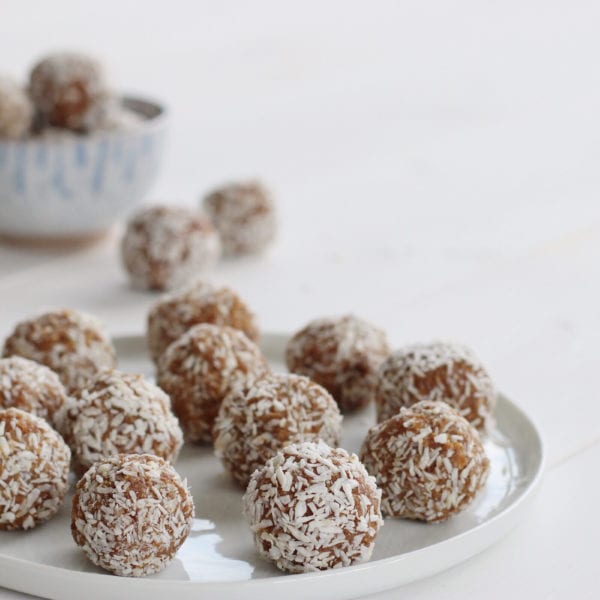 salted caramel energy balls rolled in shredded coconut served on a white plate