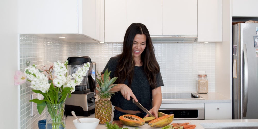 Registered Dietitian Lindsay Pleskot in the kitchen cutting a papaya.