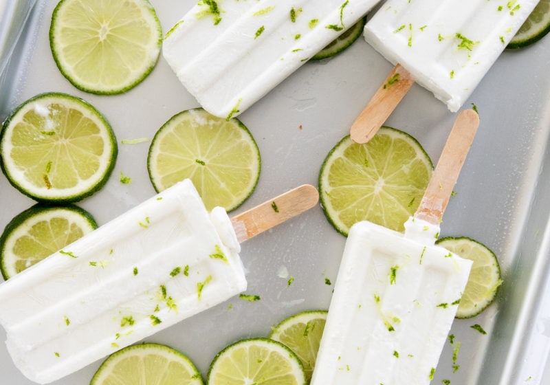 A tray of white popsicles on top of round lime circles