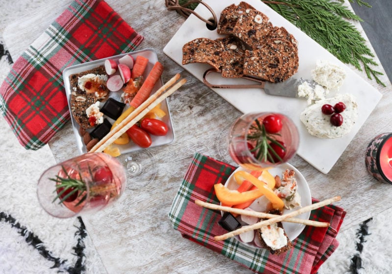 Christmas appetizers on a coffee table with chopsticks, a rectangular white serving plate, and festive kitchen towels.