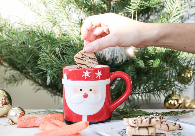 A Christmas cookie being dipped into a Santa mug.