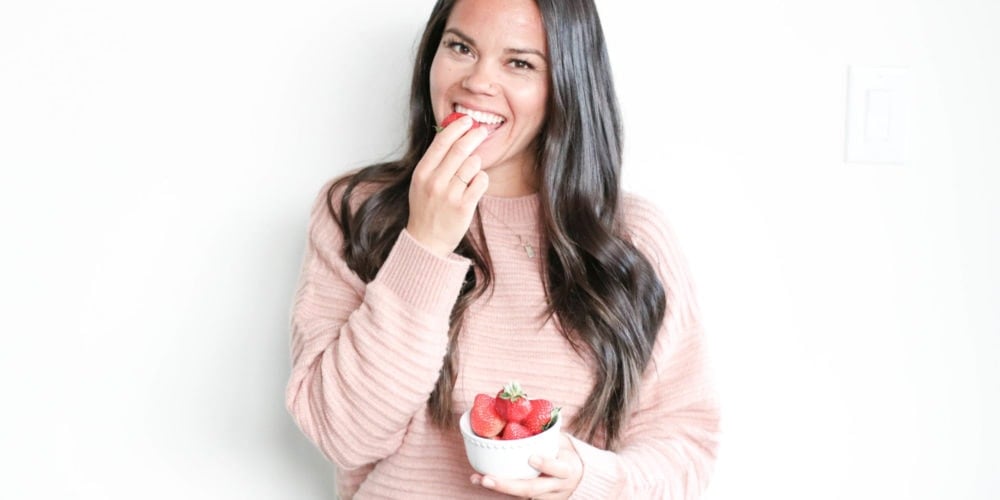 Registered Dietitian Lindsay Pleskot holding a white bowl filled with strawberries.