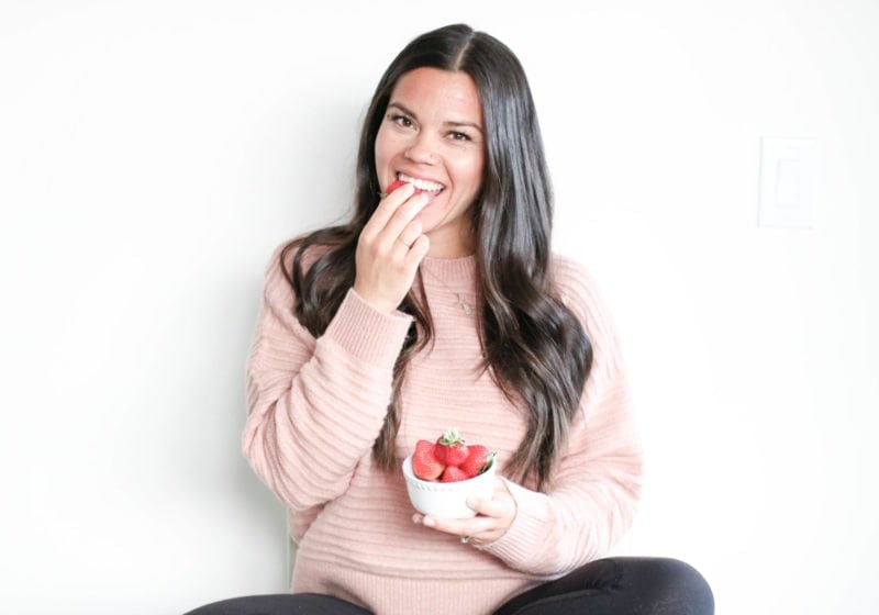 Registered Dietitian Lindsay Pleskot holding a white bowl filled with strawberries.