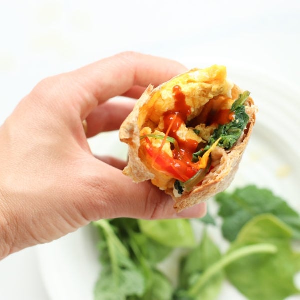 A breakfast burrito filled with spinach, onion, peppers, and feta