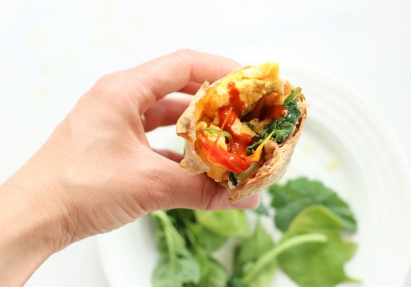 A breakfast burrito filled with spinach, onion, peppers, and feta