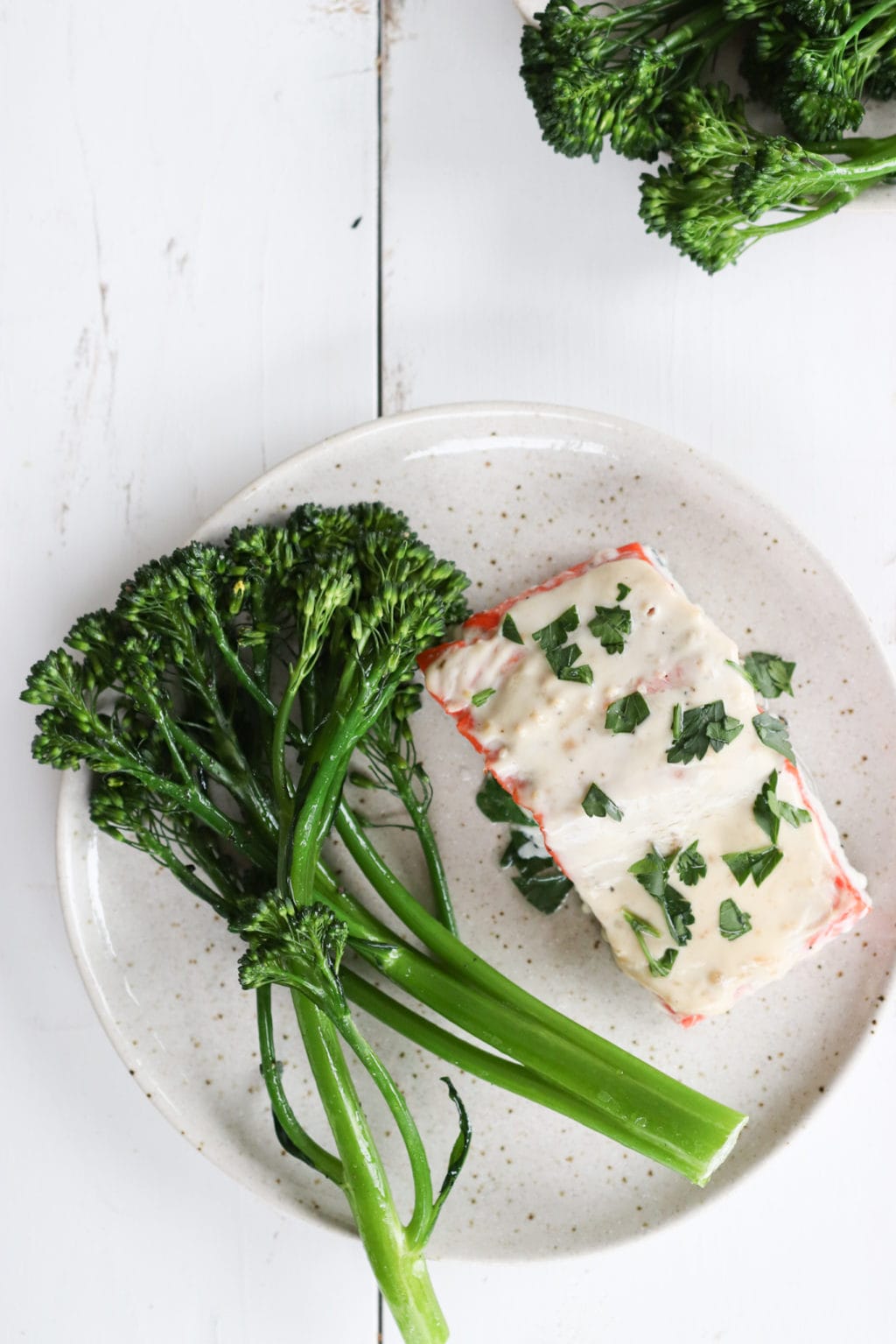 Miso-Yogurt Oven-Baked salmon on a plate with broccolini beside it. Ingredients include: salmon, plain greek yogurt, mayo, miso paste and salt and pepper.