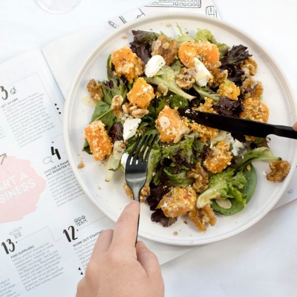Image of someone's hands using a fork and knife to eat their salad over a calendar