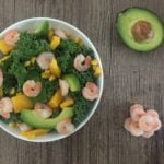 a bowl of prawn kale salad with avocado and corn
