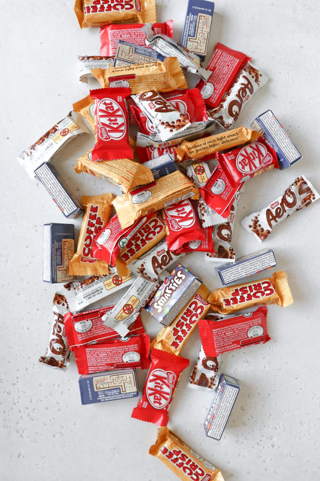 There's a pile of halloween size candy on the counter. The candies include aeros, kitkats, coffee crisps and smarties.