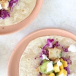 Two plates with open-faced cajun fish tacos