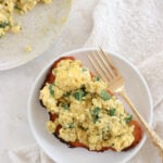 A piece of toast topped with spinach and pest cottage cheese scrambled eggs.