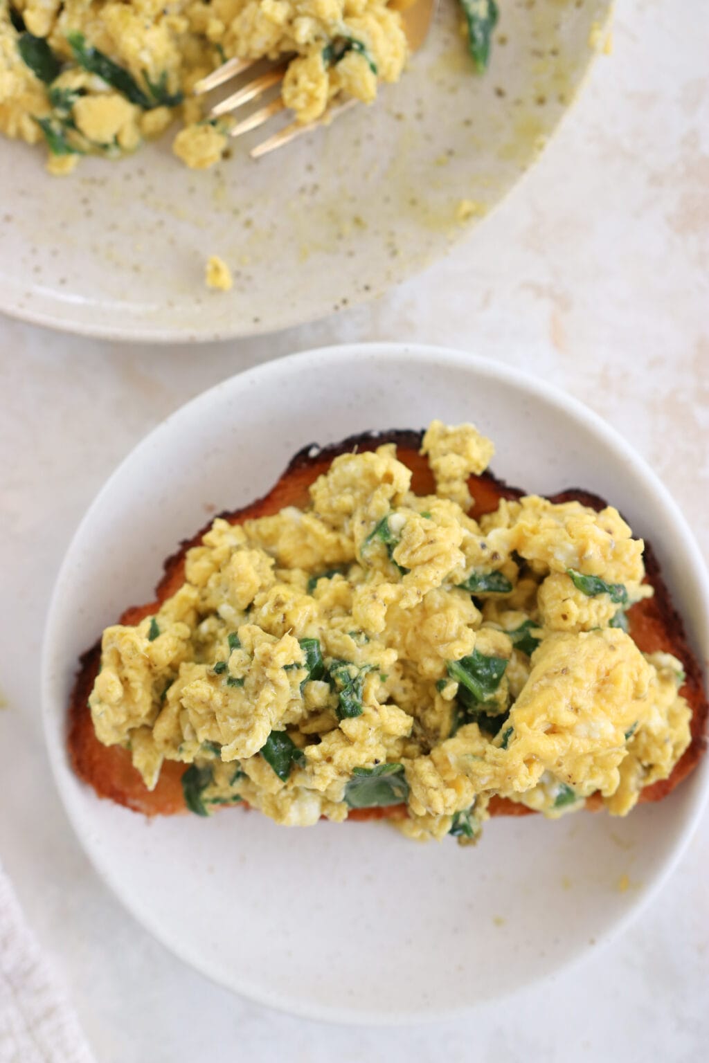 A piece of toast topped with spinach and pesto scrambled eggs. 