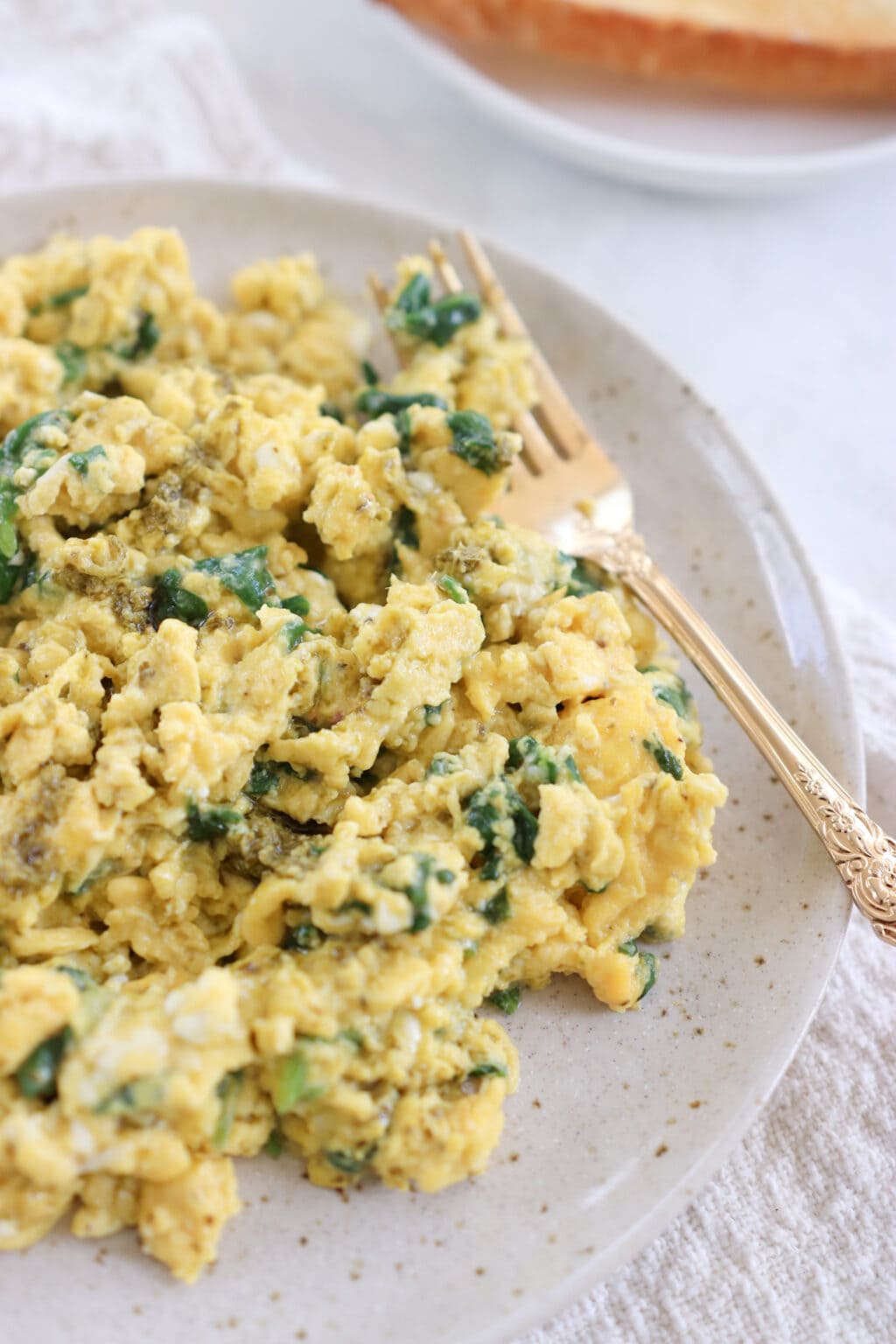 A plate of scrambled eggs with spinach in them.