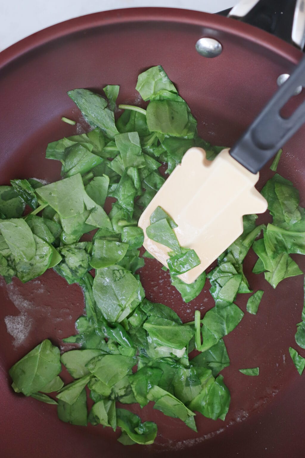 A frying pan with spinach cooking in it. 