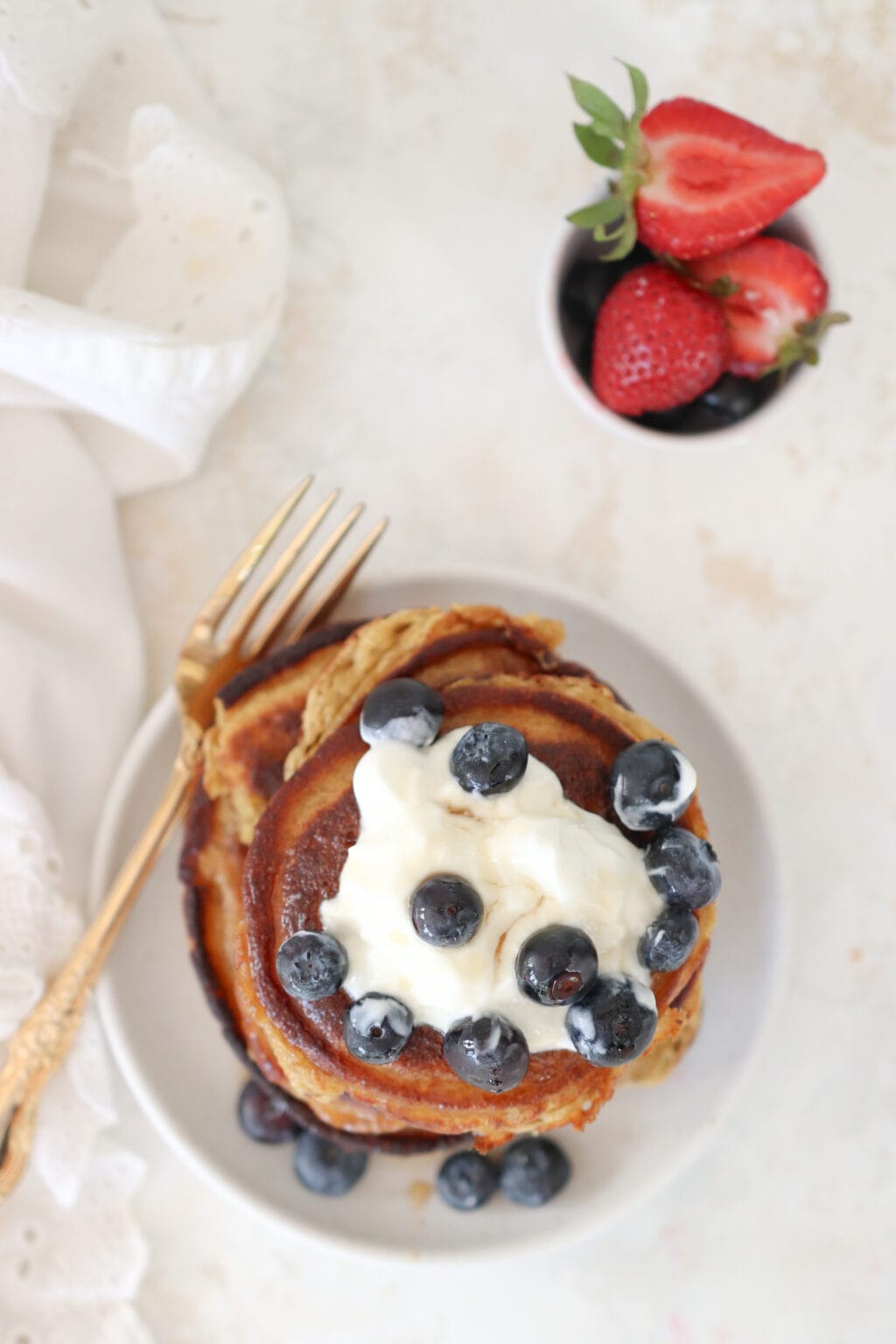 A stack of cottage cheese pancakes topped with Greek yogurt and fresh blueberries