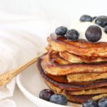 A stack of cottage cheese pancakes topped with Greek yogurt and blueberries.