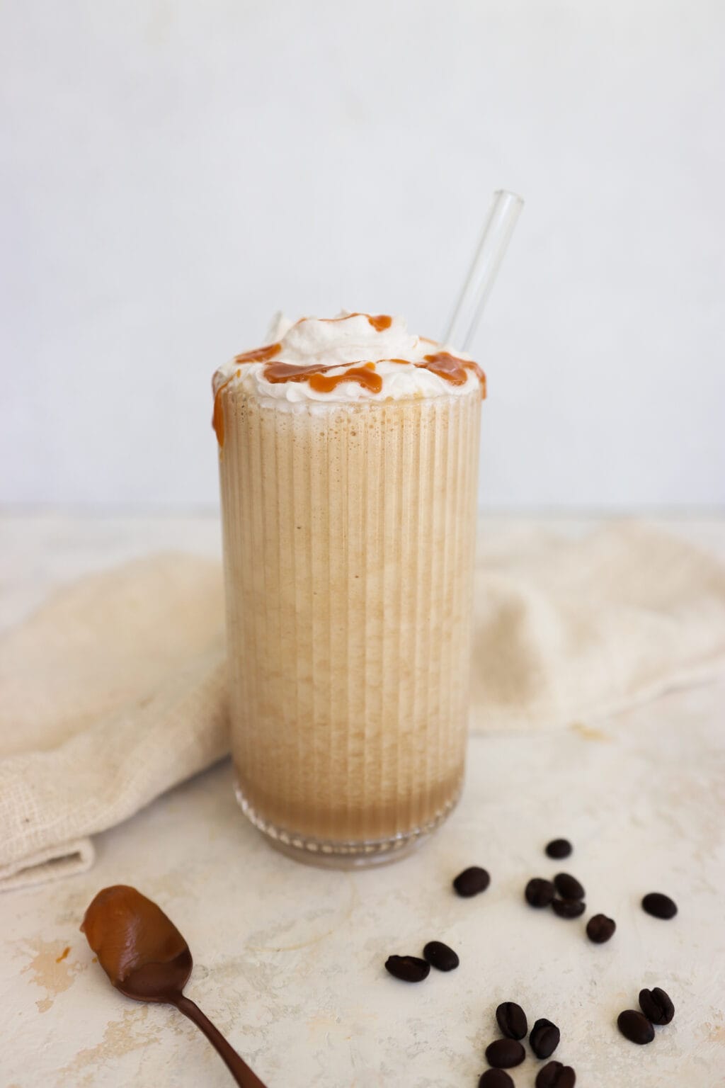 Coffee smoothie topped with whipped cream and caramel drizzle in a glass.