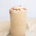 High protein coffee smoothie topped with whipped cream and caramel drizzle in a tall glass with a glass straw.