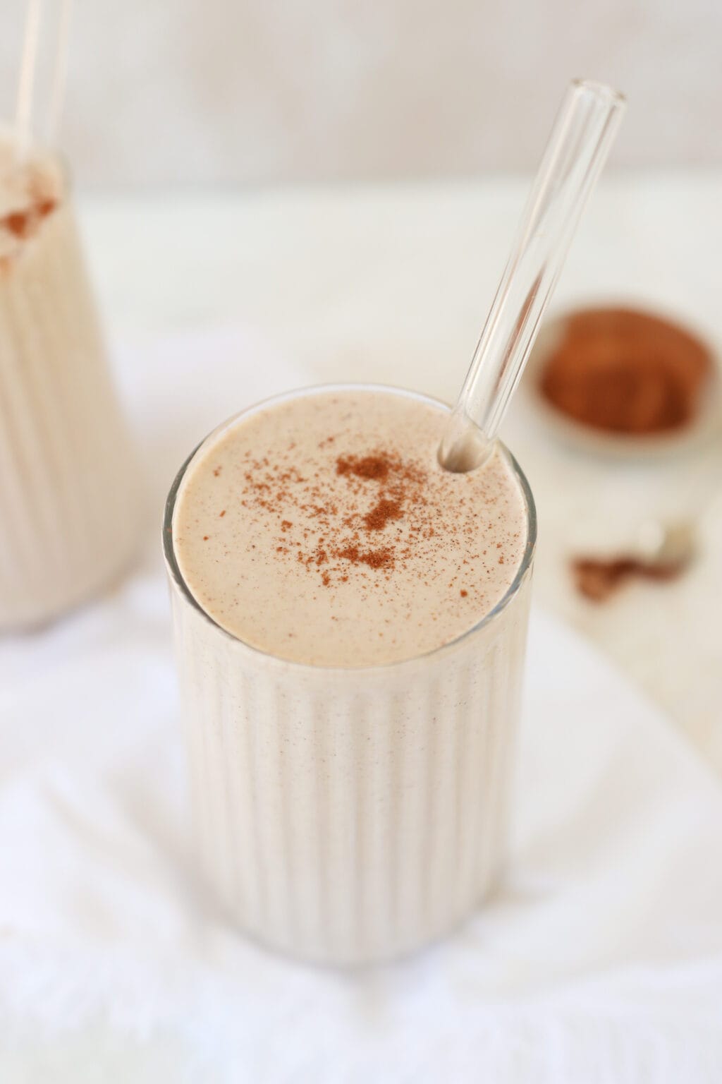 A cinnamon roll smoothie in a glass topped with ground cinnamon