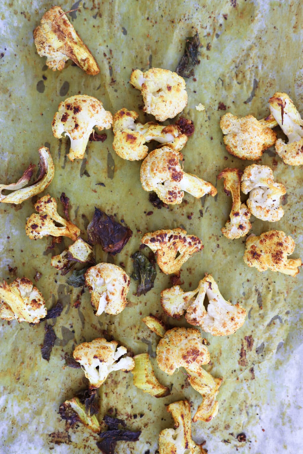 Roasted cauliflower florets on a parchment-lined baking sheet