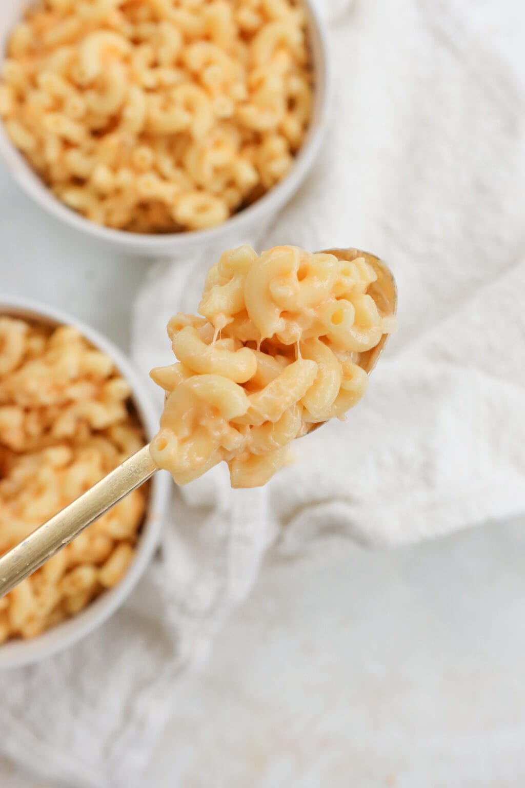 5 Ingredient Creamy Cottage Cheese Mac and Cheese in two white bowls with a scoop displayed in a spoon.