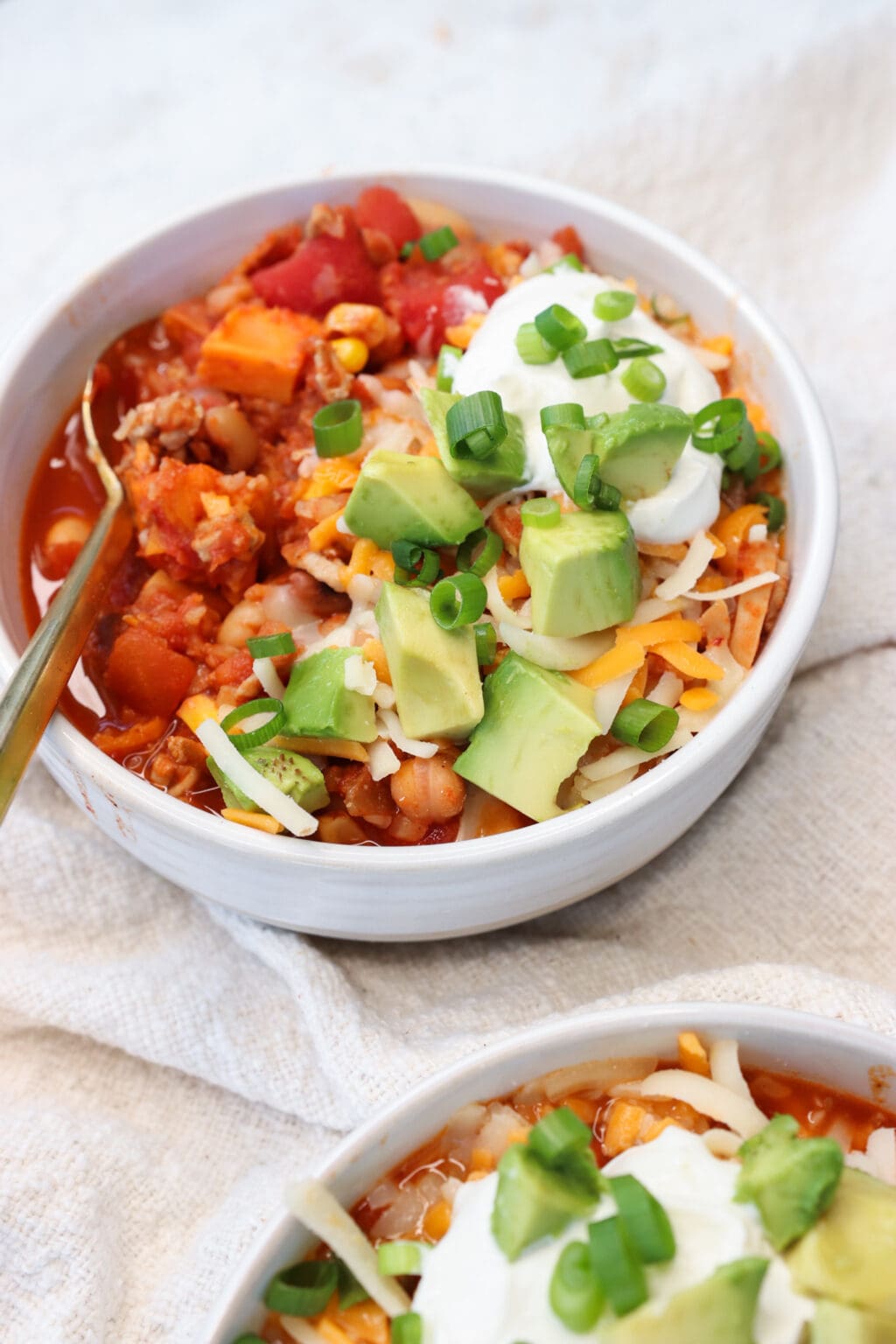 Slow Cooker Sweet Potato & Turkey Chili in two white bowls on a white table cloth