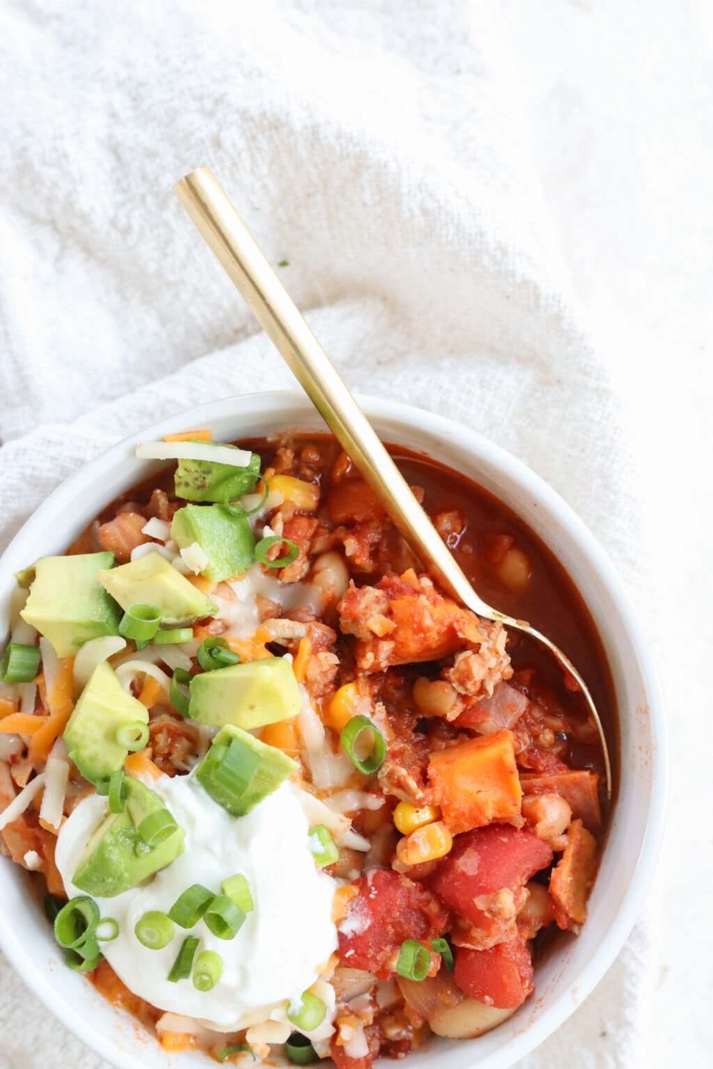 Slow Cooker Sweet Potato & Turkey Chili in a white bowl on a white table cloth