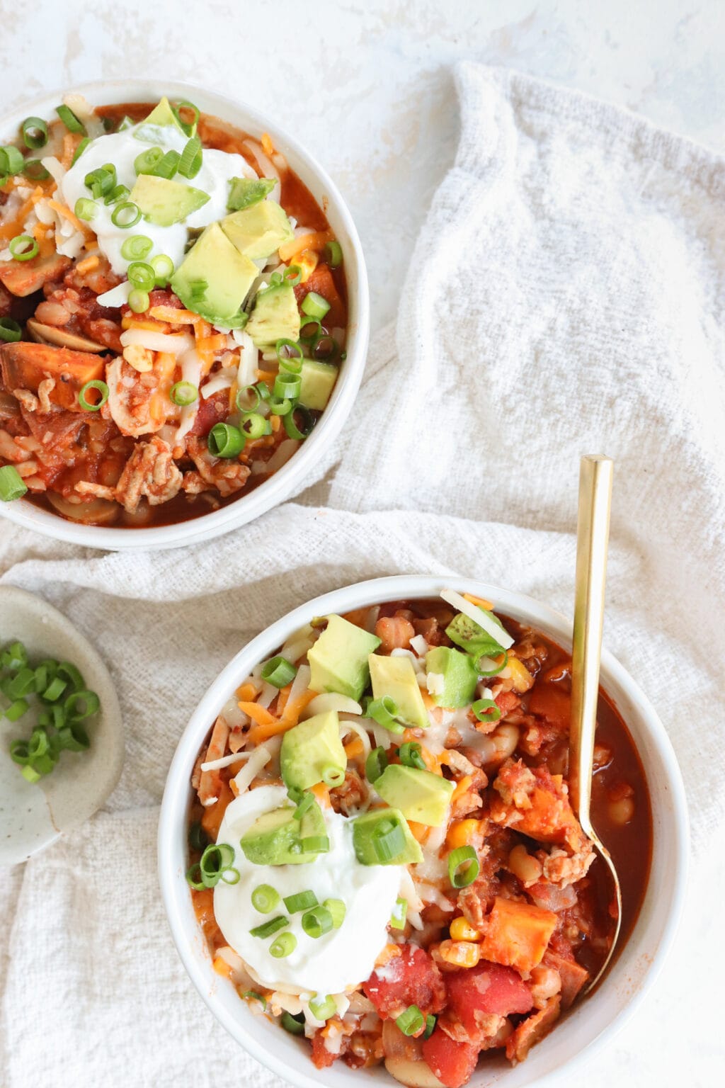 Slow Cooker Sweet Potato & Turkey Chili in two white bowls on a white table cloth