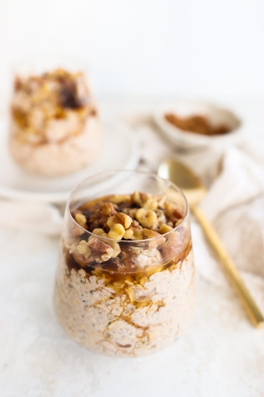 Brown sugar and Greek yogurt overnight oats in three glass bowls on top of a soft, cream-colored tablecloth with a gold spoon