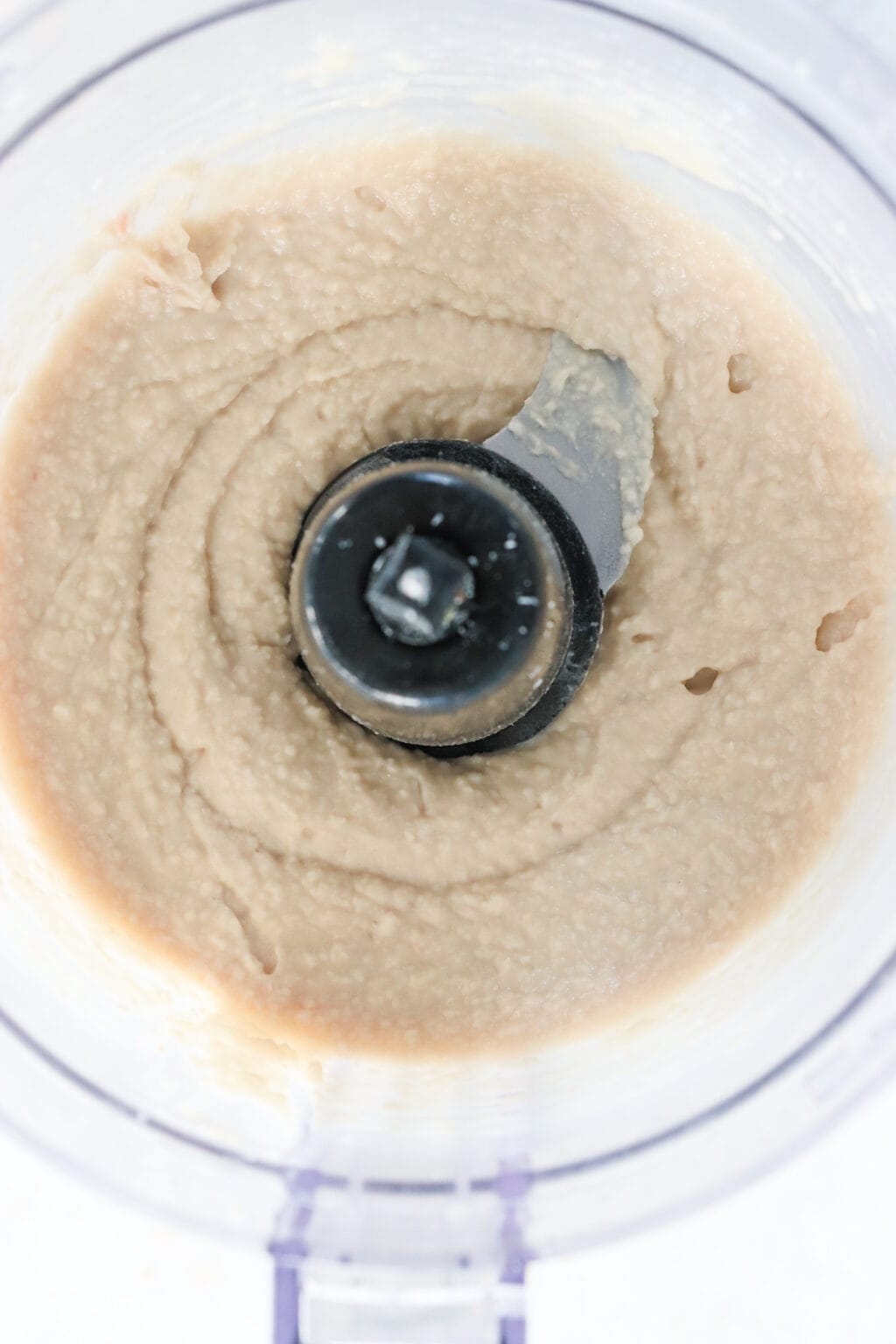 Ingredients for healthy white bean, spinach and artichoke dip, including white cannellini beans, plain Greek yogurt, olive oil, milk, garlic, salt, lemon juice, white onion, parmesan cheese, artichoke hearts, spinach, and marbled cheddar cheese blended in a food processer