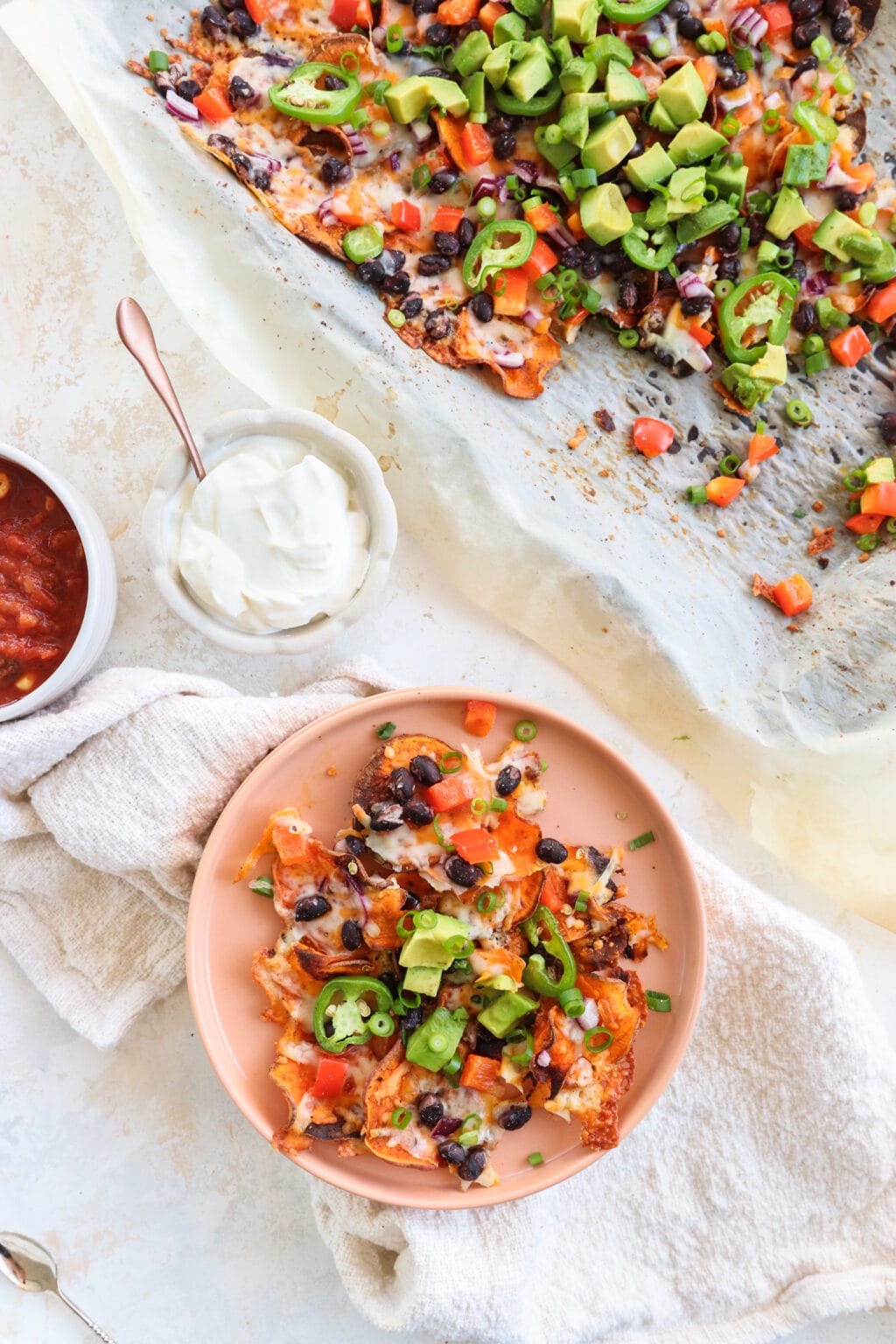 Healthy Black Bean & Bell Pepper Sweet Potato Nachos on a pink plate with salsa and sour cream