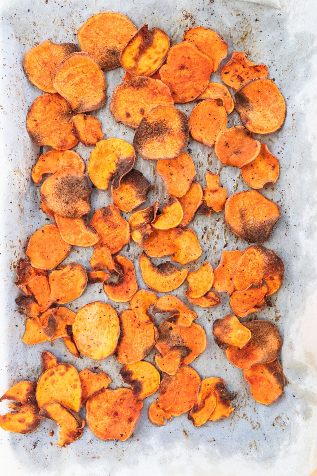Cooked sweet potato chips on a baking sheet with parchment paper