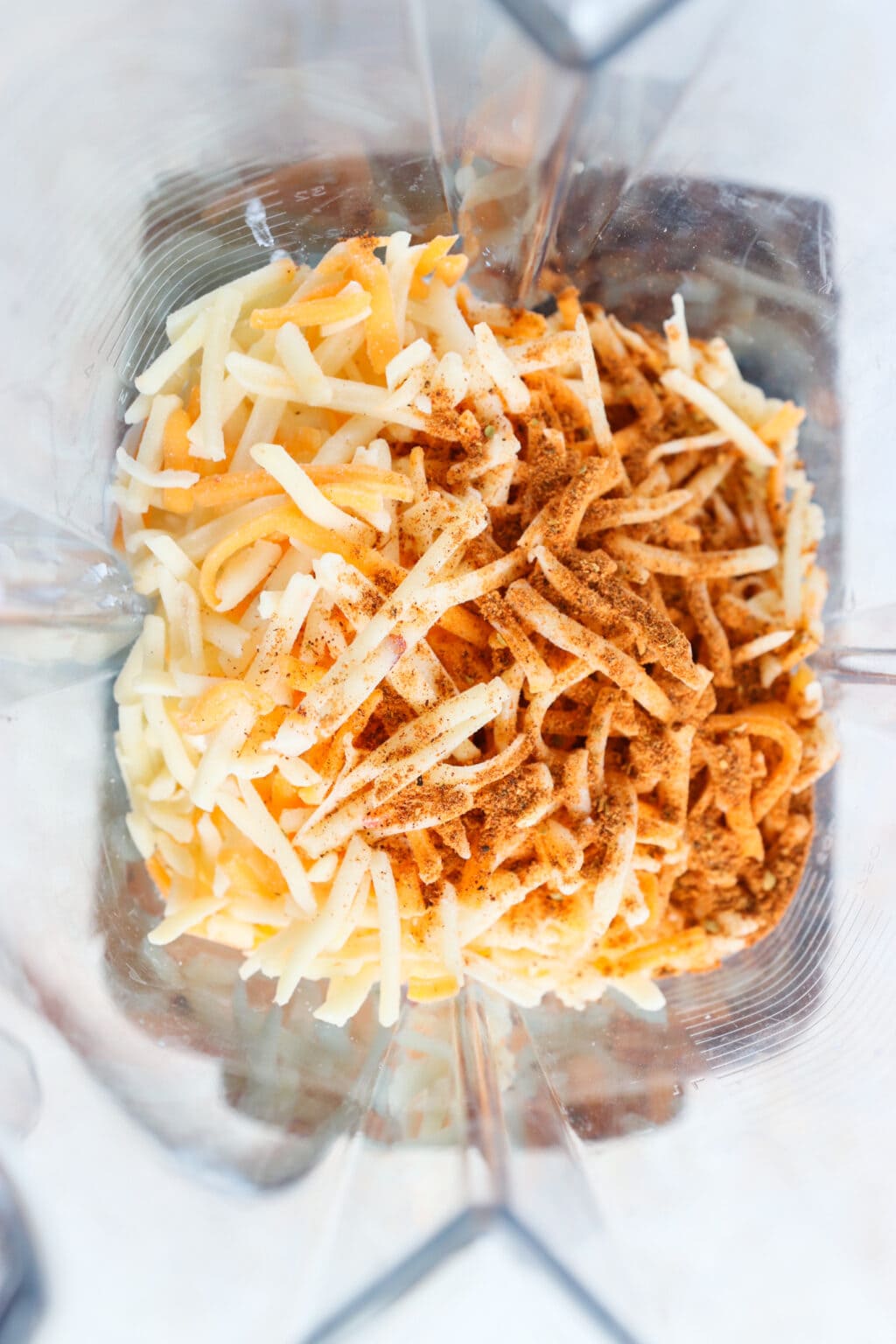 Ingredients for 5-Minute Warm Queso Dip With Cottage Cheese unblended in a blender, including, cottage cheese, shredded tex mex cheese, taco seasoning, pickled jalapenos