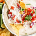 5-Minute Warm Queso Dip With Cottage Cheese in a white bowl with celery, red peppers, and tortilla chips on the side