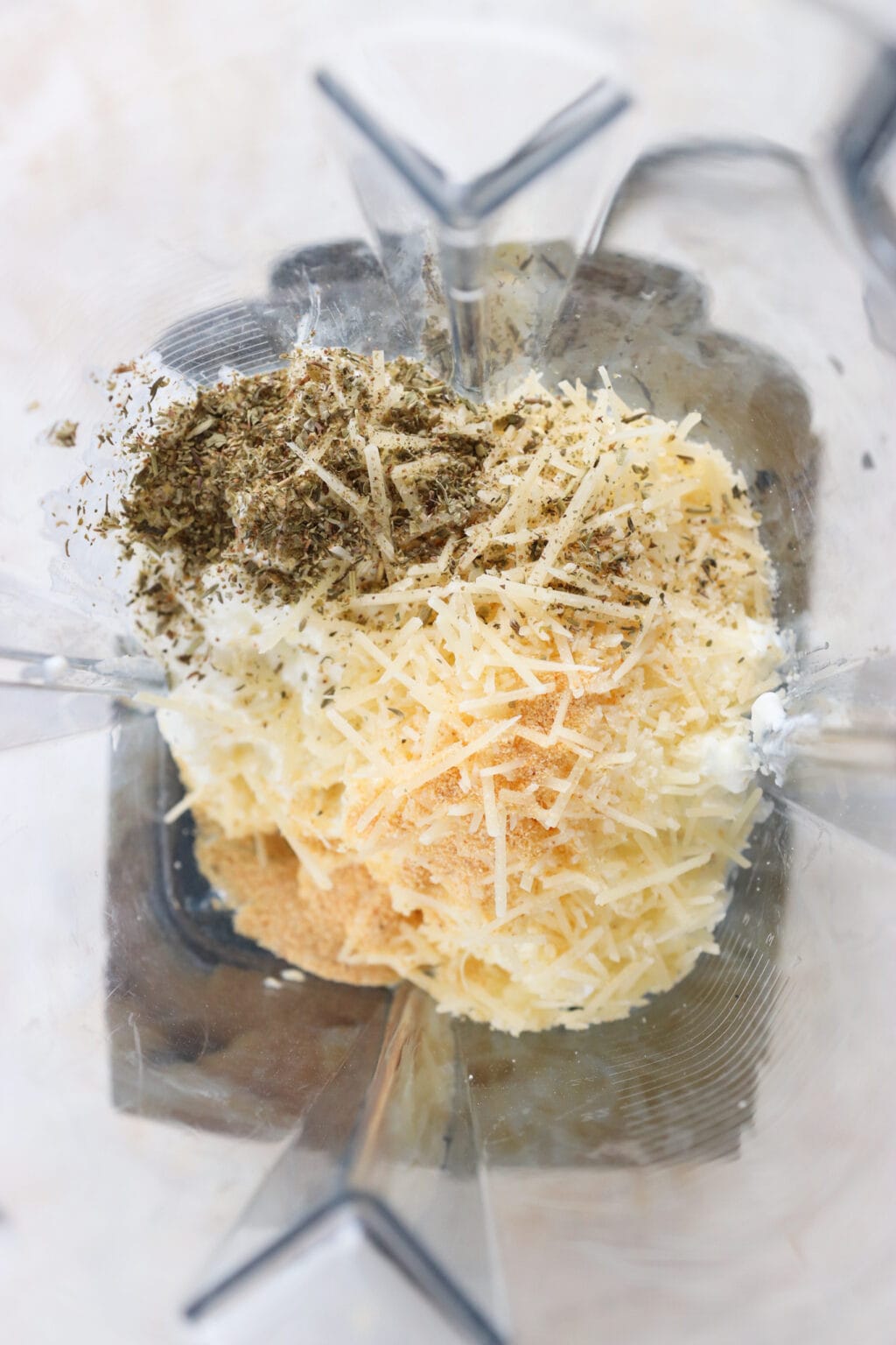 Ingredients for Quick Baked Cottage Cheese Pizza Bowl Dip unblended in a blender, including cottage cheese, parmesan cheese, garlic powder, Italian seasoning, marinara sauce, mozzarella cheese, turkey pepperoni or pepperoni