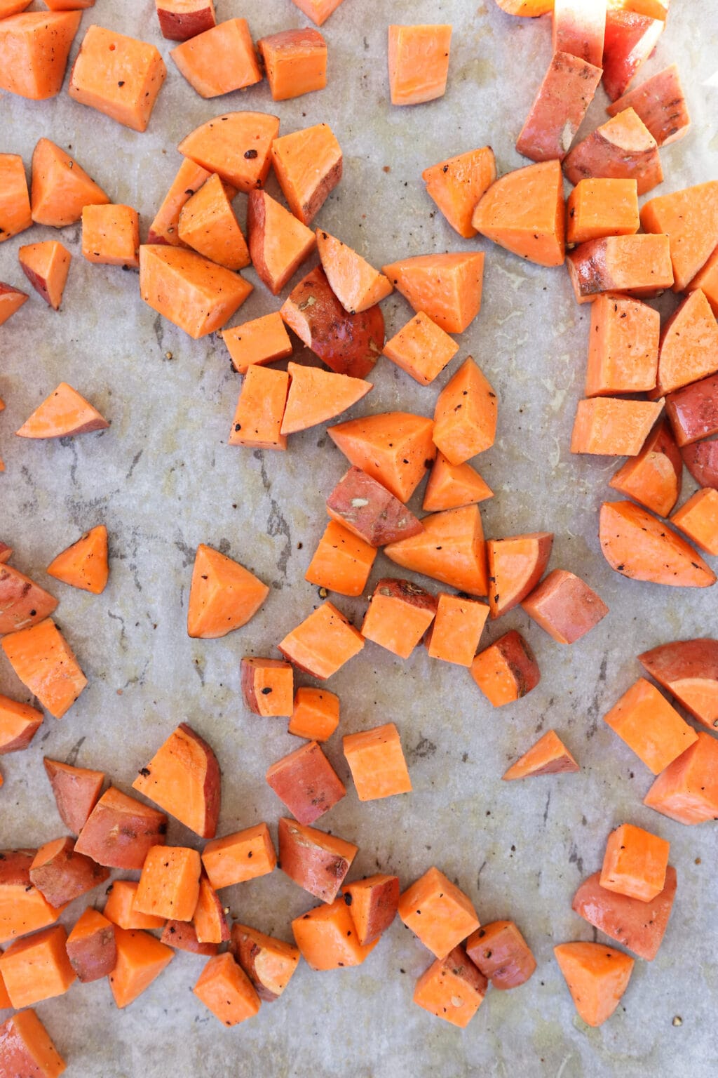 Meal prep roasted sweet potatoes uncooked on a baking sheet