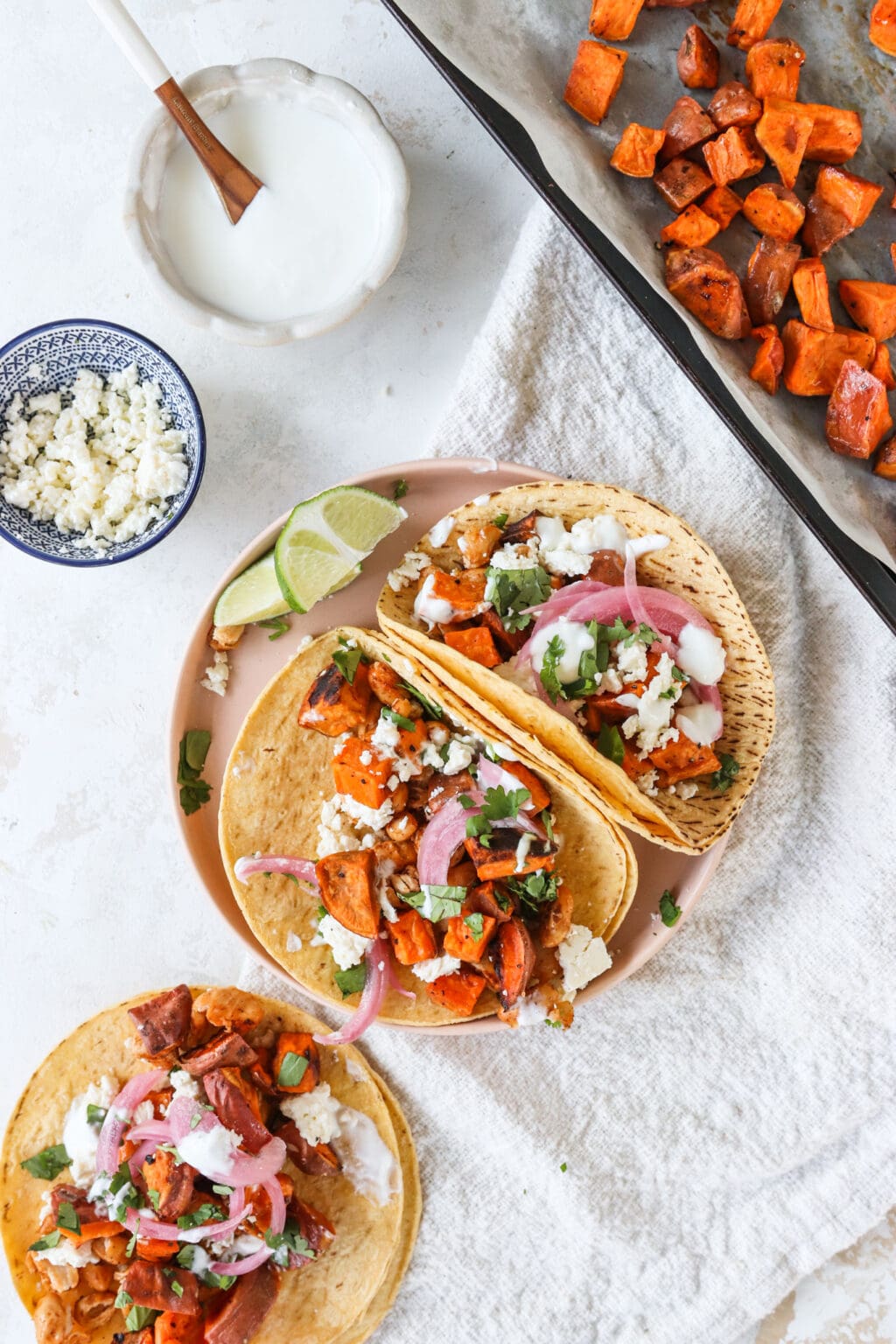 A plate of roasted white bean and sweet potato tacos with lime crema and roasted sweet potatoes on the side