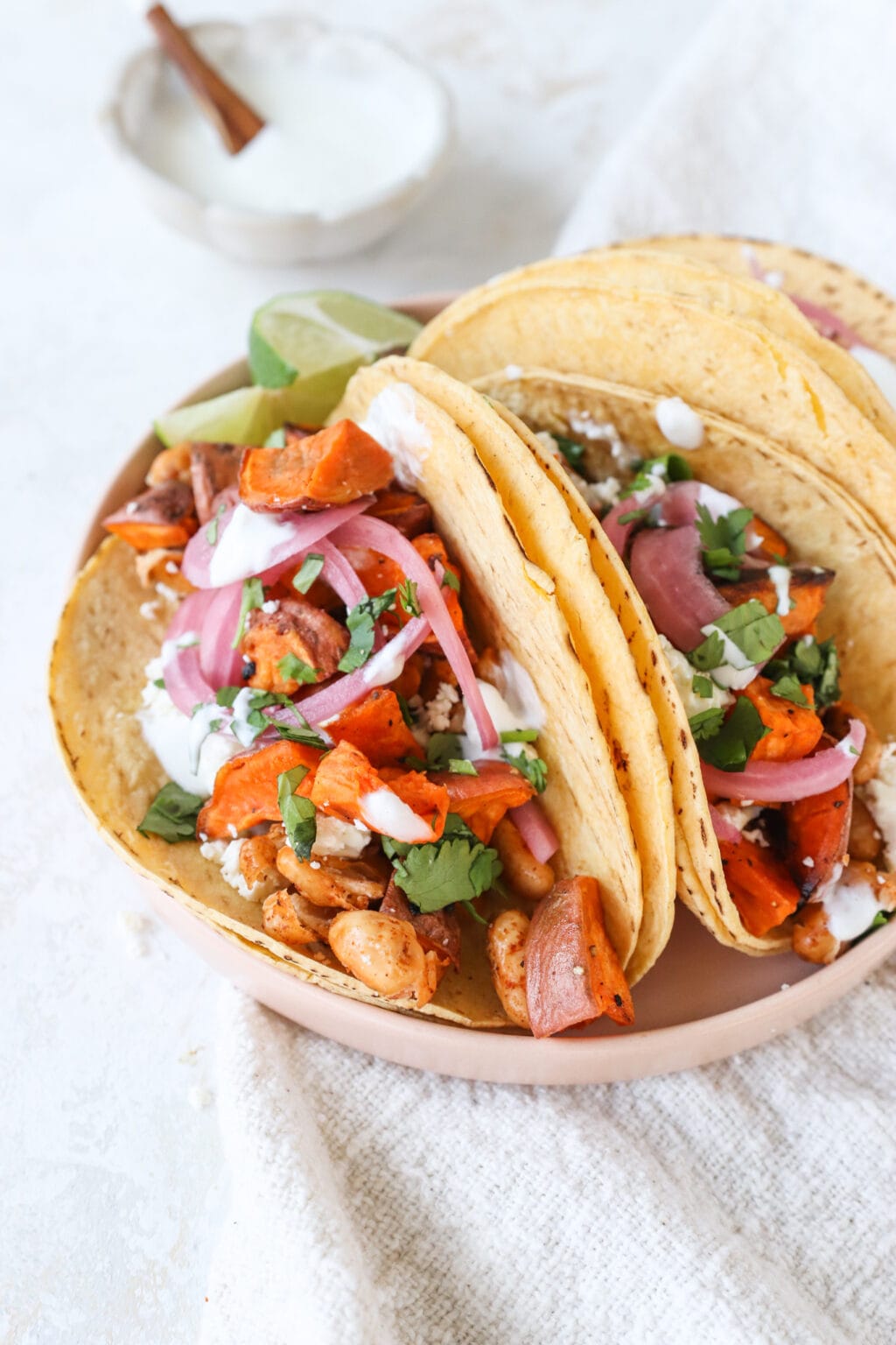 A plate of roasted white bean and sweet potato tacos with lime crema